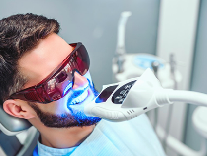 man sitting in a dentist office getting a teeth whitening procedure done